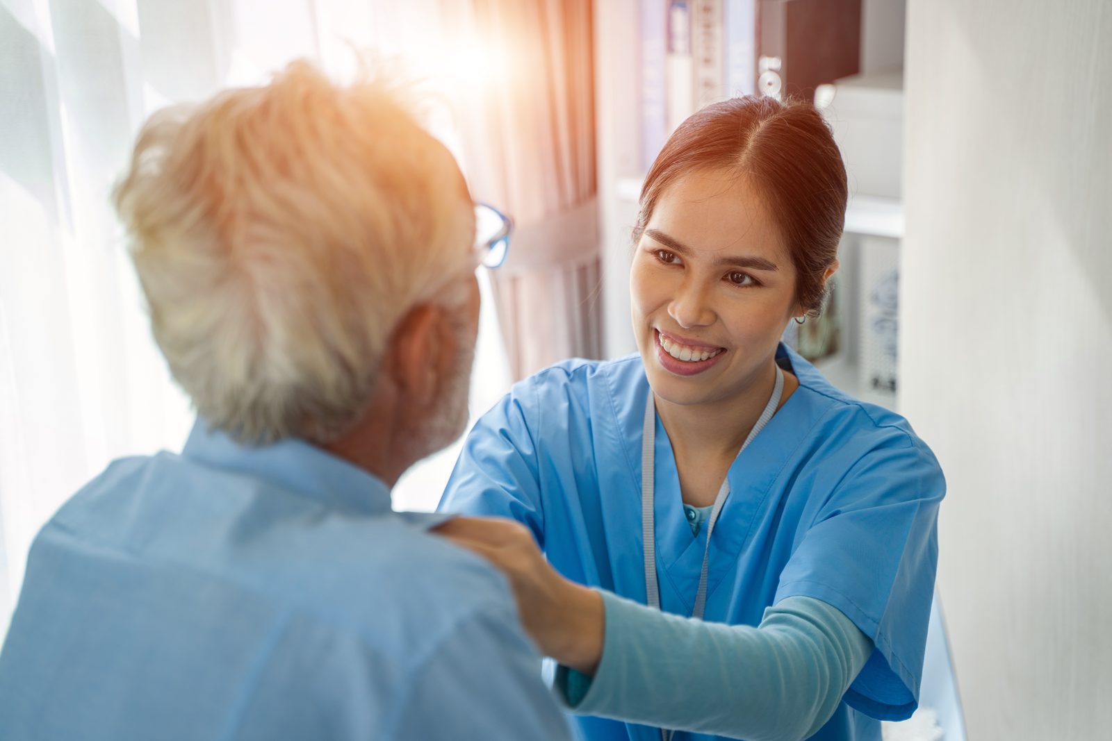 A care worker reassuring a senior man with a hand on his shoulder